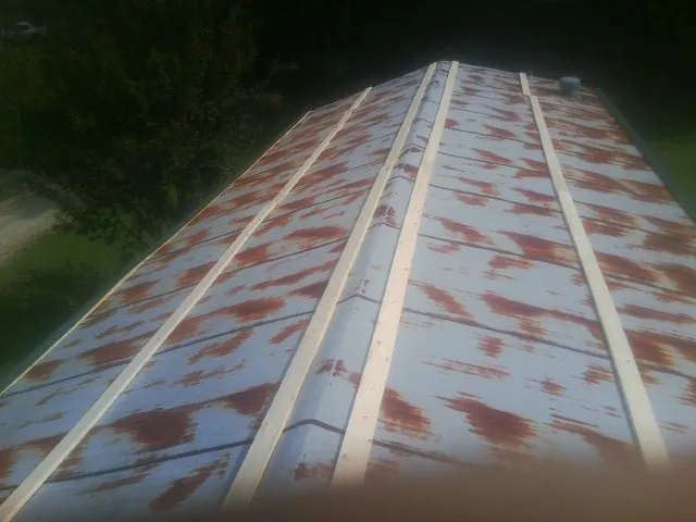 Rusted metal roof panels with new wood purlins before replacement — Storm Damage Roof Repair in Hedrick by Roofing Brothers