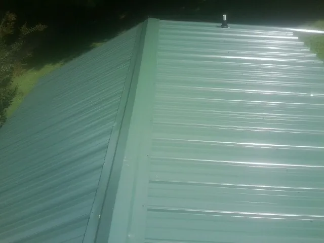 New green metal panels meeting at the ridge of a roof in Hedrick