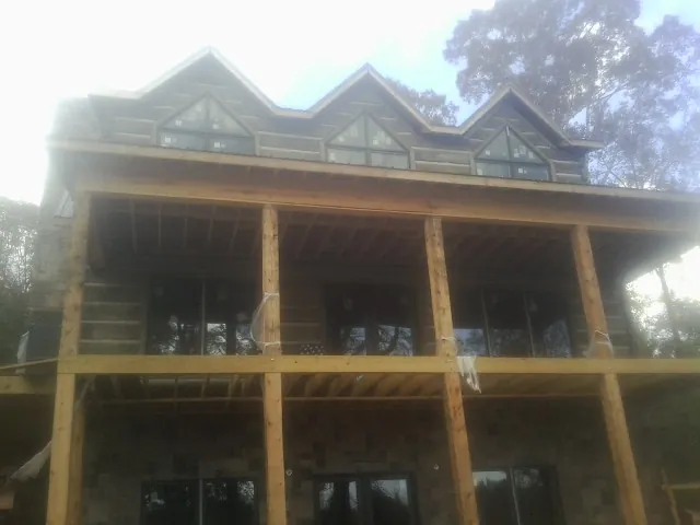 Dormers and porch framing on a large log home under construction — Roof Coating work by our crew in Hedrick