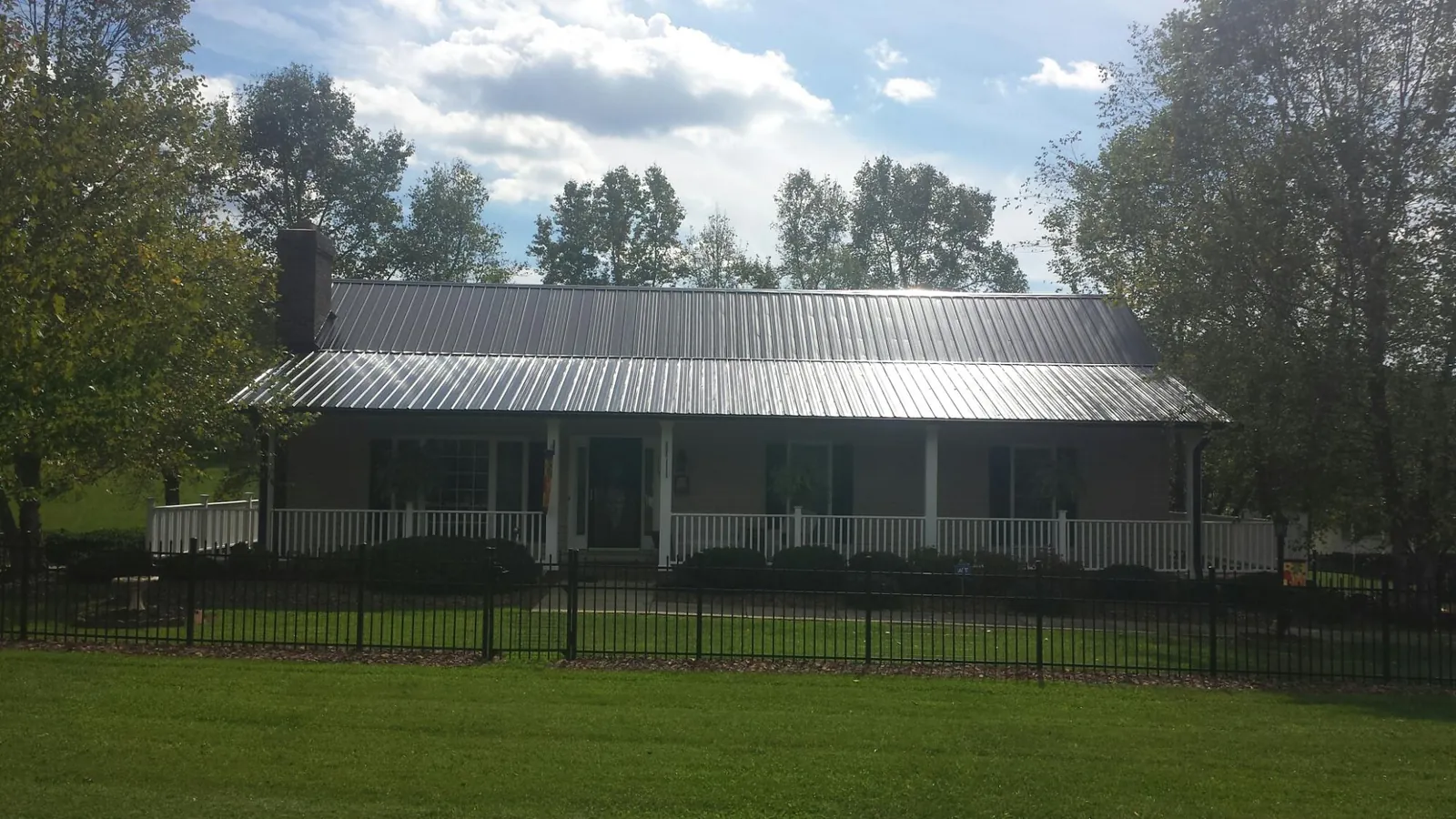Gray metal roof on a brick ranch with a full width front porch — Gutter Guard Installation work by our crew in Hedrick